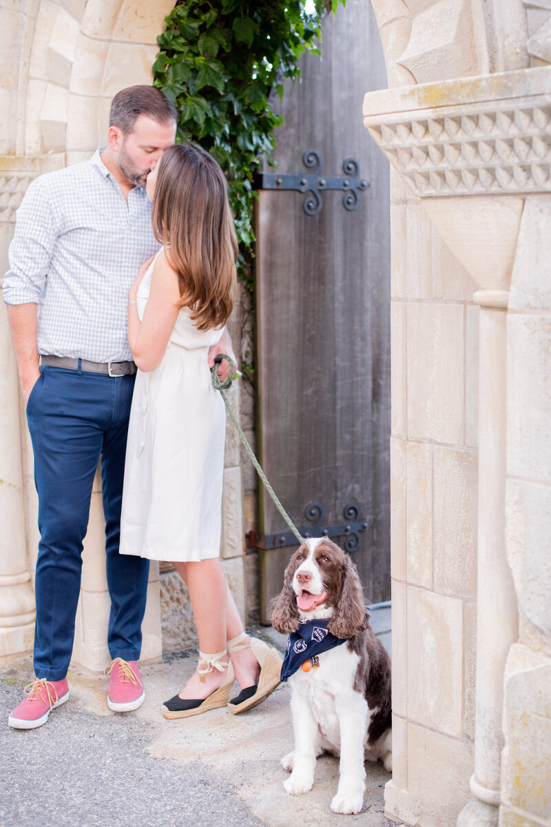 engaged couple with puppy taking engagement photos at National Cathedral engagement session